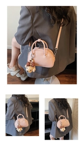 Vue détaillée du sac baguette rose avec double poignée et breloque ours en peluche