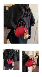 Détail du sac baguette en cuir rouge avec un charm ours en peluche et un nœud à pois