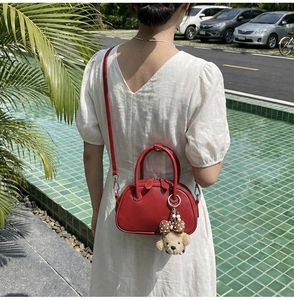 Photo mode d'un sac bowling en cuir rouge avec un charmant ours pour femme en plein air