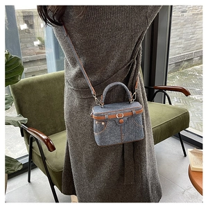 Detail of retro denim box bag with brown leather trim and silver metal hardware