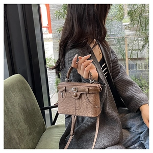 Detail view of a vintage brown box bag with textured leather and decorative buckle straps