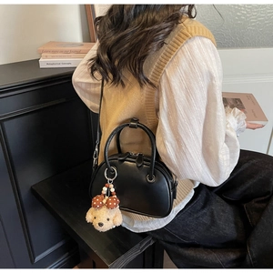 Détail du sac bandoulière noir demi-lune avec finition mate et breloque peluche chien