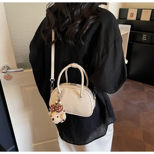 Détail d'un mini sac bowling porté croisé avec un pendentif chien en peluche doux