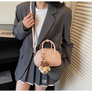 Détail d'un sac à main en cuir rose avec un joli accessoire de charme en peluche d'ours