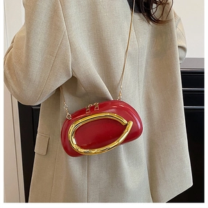 Detailed side view of a red matte leather clutch bag with a unique gold metal buckle
