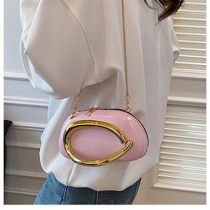 Pink semi-oval mini crossbody bag with prominent gold curved metal hardware and chain strap