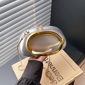 Detail of silver half-moon evening bag with a large gold oval handle and chain strap