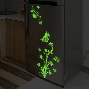 Glow-in-the-dark butterfly and floral vine stickers glowing green on a gray refrigerator