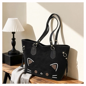 Detail of minimalist cat face print and gold metal rings on a black tote bag
