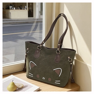 Detail of dark green tote bag featuring a cute cat face design and leather handles