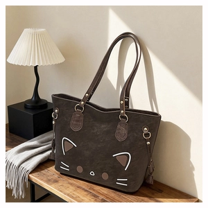 Detail of dark brown faux suede tote bag with cat face design and tassel charm