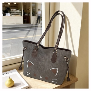 Detail of grey tote bag featuring a cute cat face print and brown shoulder straps