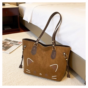 Close-up of caramel brown suede tote bag featuring a cute cat face and tassel detail