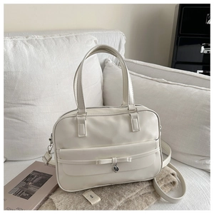 Detail of a beige PU leather shoulder bag featuring a bow and heart-shaped metal pendant