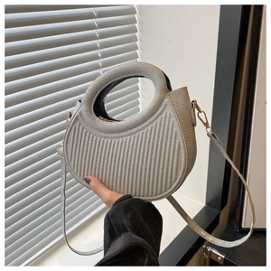 Detail of silver metallic handbag with unique vertical pleats and round cutout handle