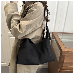 Detail view of large black suede tote bag showing side buckle and spacious interior drape