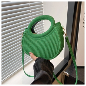 Close-up of green glitter half-moon handbag with gold hardware and curved handle