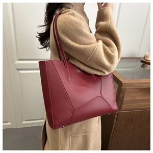 Detail of burgundy leather tote bag with geometric stitching and metal feet
