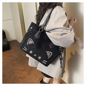 Detailed close-up of a black suede cat motif tote bag worn with a beige trench coat