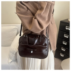 Detail of vintage brown bowling bag featuring a slim bow and silver heart pendant charm