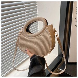 Detail of golden crescent bag showing woven texture and integrated circular handle