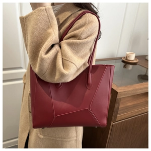 Close-up of deep red tote bag with geometric stitching and smooth leather texture