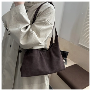 Detail of dark brown suede shoulder bag with matte texture and decorative center stitching