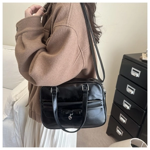Detail of black faux leather tote bag with bow tie, silver heart charm and adjustable strap