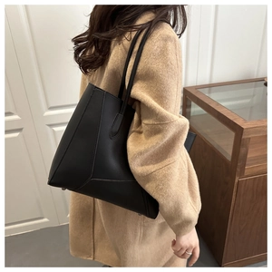 Side view of black matte leather tote bag with reinforced base and long shoulder straps