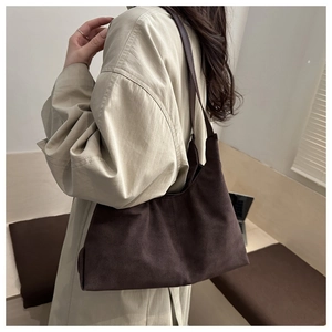 Detail view of a vintage dark brown suede tote bag worn as a chic underarm shoulder bag