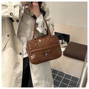 Detail of vintage brown patent leather handbag with bow and silver heart pendant charm