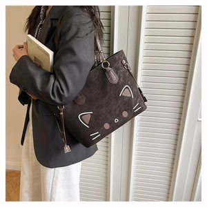 Détail d'un grand sac fourre-tout marron avec motif de chat porté sur un blazer noir