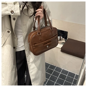 Detailed view of brown leather bowling bag with bow decoration and silver heart charm