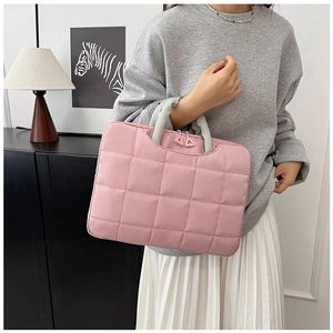 Close-up of pink quilted 14-inch laptop bag with light green handles and soft fabric texture
