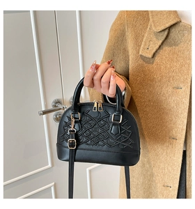 Close-up of black shell handbag with woven embroidery and golden metallic accents