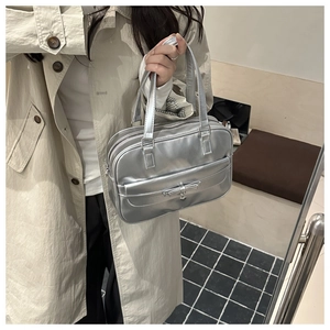 Detail of silver metallic bowling bag with bow decoration and heart pendant on shoulder