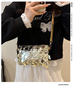 Detailed macro view of sparkling silver sequin texture and golden metal strap on crossbody bag