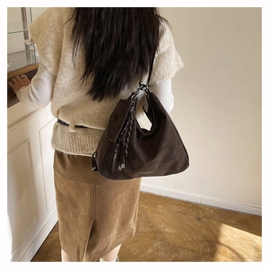 Detalle del bolso Hobo de ante marrón oscuro con cremallera lateral y borla larga