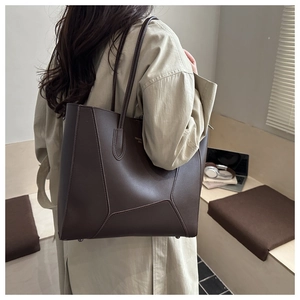 Detail of dark brown tote bag with geometric stitching shown on model shoulder
