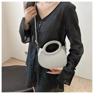 Close-up of semi-circle silver glitter handbag with textured lines and gold hardware