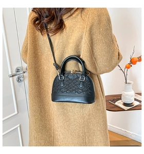 Detail shot of black shell bag with wave pattern worn over a warm woolen coat