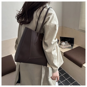 Detail showing deep brown leather tote bag with stitching and shoulder straps on a model