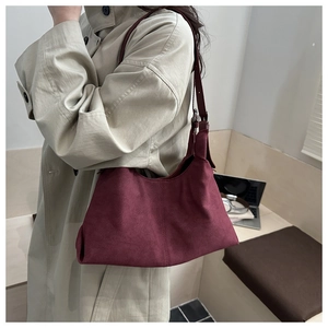 Detail of burgundy suede hobo bag with adjustable strap and silver metal buckle