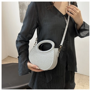 Détail du mini sac croissant tissé argenté avec poignée ronde et finitions dorées chic