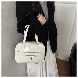 Close-up of cream white glossy tote bag featuring a bow and silver heart pendant detail
