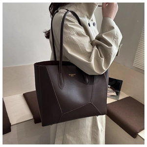 Detail of a dark brown leather tote bag featuring geometric stitching and long straps