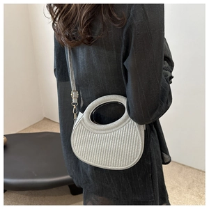 Close-up of a silver textured handbag with a circular handle and detachable shoulder strap