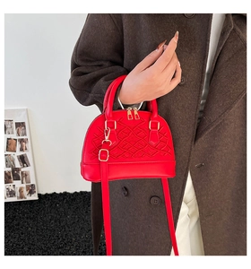 Detail der roten Muschel-Handtasche mit gewebter Prägestruktur und Goldbeschlägen