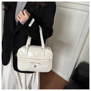 Detail of cream white faux leather handbag with ribbon bow and silver heart charm