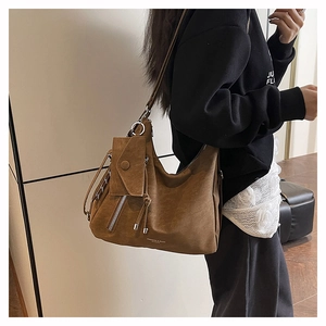 Vue détaillée d'un grand sac à bandoulière mat caramel avec pompon et décoration